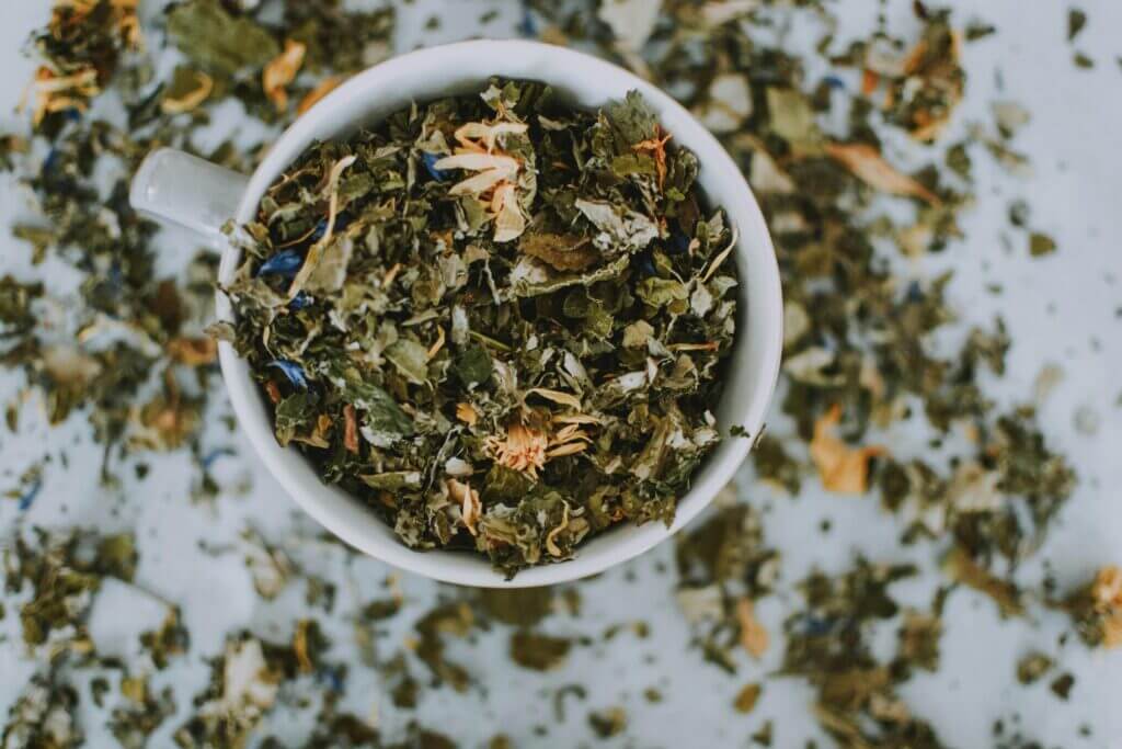 Ayurveda The Science of Life - Overhead shot of a cup with a blend of dried herbal tea leaves and flowers.