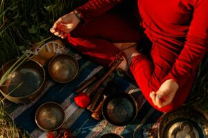 A person meditating outdoors with Tibetan singing bowls, creating a peaceful atmosphere.